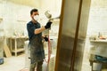 Male worker painting a brown door in a woodshop