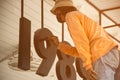 Male worker paints black numbers of shop with paint brushes