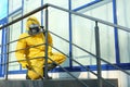 Male worker in protective suit spraying insecticide on stairs. Pest control