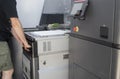 Male worker pushes working chamber with white polyamide powder into 3D printer.