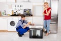 Male Worker Repairing Oven Using Multimeter In Kitchen Royalty Free Stock Photo