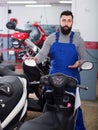 Male worker showing scooters in motorcycle workshop Royalty Free Stock Photo