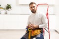 Male Worker Sitting on the Ladder on Construction Site. Repair Home and House Renovation Service Royalty Free Stock Photo