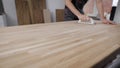 Male worker standing holding tool and buffering wooden board indoors