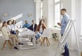 Male worker standing by office whiteboard and making business presentation for team of people Royalty Free Stock Photo