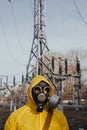 male worker standing on territory of power station. Environmentalist wearing protective uniform, gas mask.