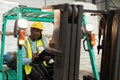 Male worker talking on mobile phone and writing on clipboard in forklift Royalty Free Stock Photo