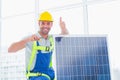 Male worker tightening solar panel while gesturing thumbs up