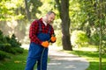 Male worker in uniform watering plants using garden hose Royalty Free Stock Photo