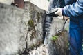 Male Worker using industrial construction tool, industrial jackhammer with demolition debris and cement