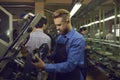 Male worker using industrial press while making new sneakers at footwear factory