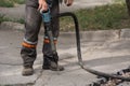 Male worker using jackhammer pneumatic drill machinery on road repair