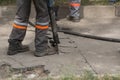 Male worker using jackhammer pneumatic drill machinery on road repair