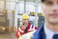Male worker using walkie-talkie with colleague in foreground at shipyard Royalty Free Stock Photo