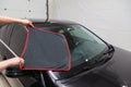 A male worker washes a black car, wiping water with a soft cloth and microfiber, cleaning the surface to shine in a vehicle Royalty Free Stock Photo