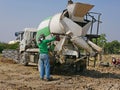 A male worker washing / cleaning a cement mixer truck after finish pouring out the concrete