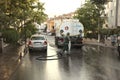 Male worker washing and disinfecting a street