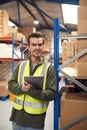 Male Worker Wearing High-Vis Vest Inside Warehouse Checking Stock On Shelves Using Digital Tablet Royalty Free Stock Photo