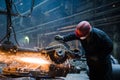 Male worker wearing special protective gloves, cutting metal with big electric grinder, orange sparks flying during