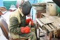 A male worker a welder in a protective mask welds a metal pipe at a welding station in a workshop at a metallurgical plant Royalty Free Stock Photo