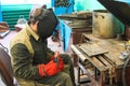 A male worker a welder in a protective mask welds a metal pipe at a welding station in a workshop at a metallurgical plant Royalty Free Stock Photo