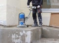 male worker works with the diamond grinding machine, polishing the porch in front of the office building. the cement floor and co