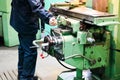 A male worker works on a larger metal iron locksmith lathe, equipment for repairs, metal work in a workshop at a metallurgical