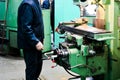 A male worker works on a larger metal iron locksmith lathe, equipment for repairs, metal work in a workshop at a metallurgical