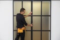 male workers carpenters installing interior glass door with a wooden frame at new luxury apartment.