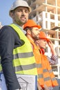 Male workers engineers at construction site in helmets hardhats. High-rise building skyscraper background Royalty Free Stock Photo