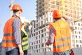 Male workers engineers at construction site in helmets hardhats look at high-rise building skyscraper Royalty Free Stock Photo