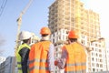 Male workers engineers at construction site real estate in helmets hardhats look at high-rise building skyscraper Royalty Free Stock Photo