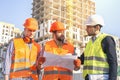 Male workers engineers at construction site in helmets hardhats near high-rise building skyscraper Royalty Free Stock Photo