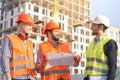 Male workers engineers at construction site in helmets hardhats near high-rise building skyscraper Royalty Free Stock Photo