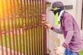 Male workers are using a paint sprayer at a steel door. Workers spray paint must be protected from inhalation by using cloth to co