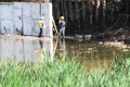 Male workers in the water. Preparing the site for containment pond. Park forest background Royalty Free Stock Photo