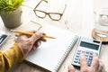 Male working with calculator and notepad on worktable.