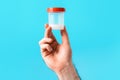 A male& x27;s hand is holding a plastic jar with a sperm analysis in close-up. Blue background. The concept of a sperm Royalty Free Stock Photo