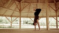 Male yoga practician performs the stand on arms in the training hall with wooden dome