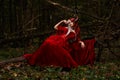 Maleficent Woman in Red Clothing and Horns in dark Forest. Posing in magik forest Royalty Free Stock Photo