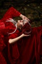 Maleficent Woman in Red Clothing and Horns in dark Forest. Posing in magik forest Royalty Free Stock Photo