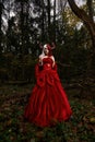 Maleficent Woman in Red Clothing and Horns in dark Forest. Posing in magik forest Royalty Free Stock Photo