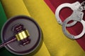 Mali flag with judge mallet and handcuffs in dark room. Concept of criminal and punishment, background for judgement