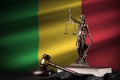Mali flag with statue of lady justice, constitution and judge hammer on black drapery. Concept of judgement and guilt