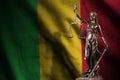 Mali flag with statue of lady justice and judicial scales in dark room. Concept of judgement and punishment