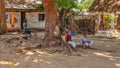 Malindi, Kenya - April 06, 2015: Unknown local kids sitting on tree root in front of their house. Living conditions in this area