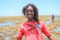 Black African young guy with dreadlocks laughs cheerfully and holds a starfish against the backdrop of the Indian Ocean. Beach li