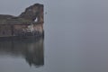 Mallards swimming next to an ancient pier of a lake on a foggy day in an italian town Royalty Free Stock Photo