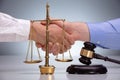 Gavel In Front Of Two Men Shaking Hands Royalty Free Stock Photo