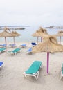 Parasols and sun lounges on Cala Estancia beach before rain. Royalty Free Stock Photo